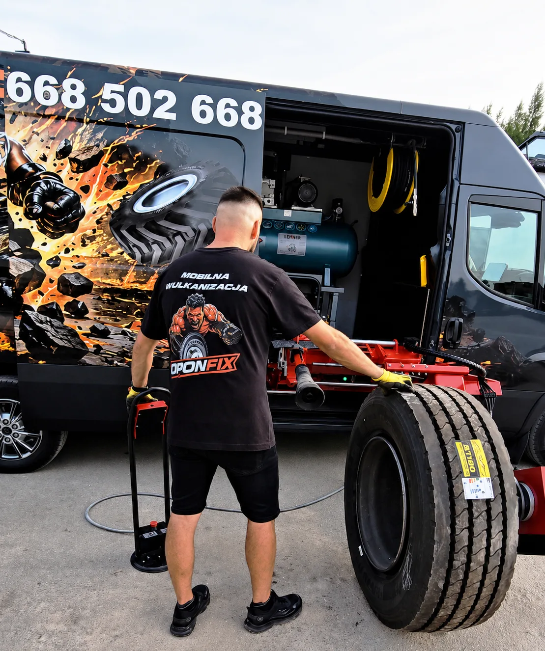 OPONFIX-Mechaniker rollt einen LKW-Reifen am Fahrzeug